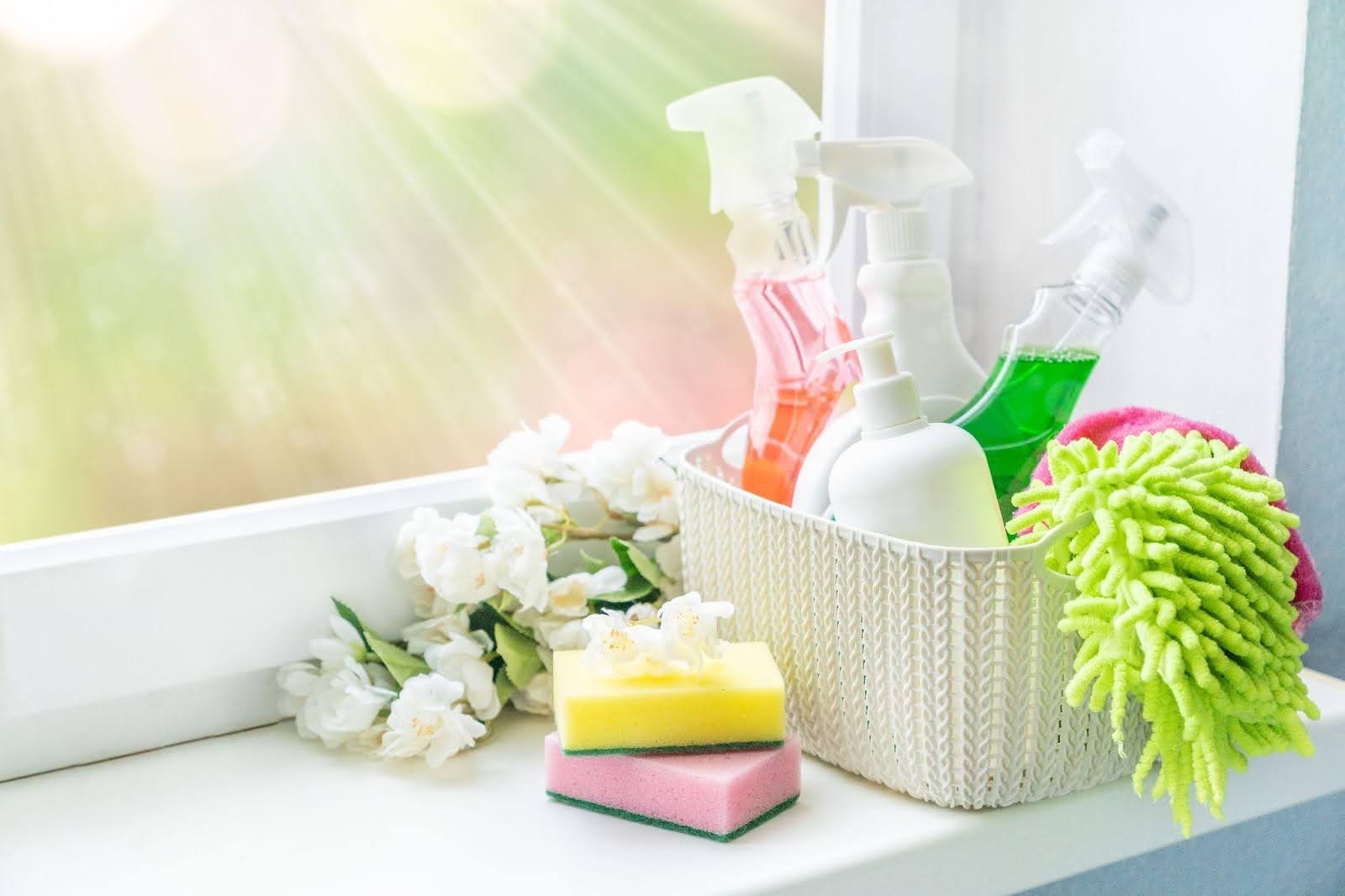 A variety of colorful cleaning products arranged on a window sill