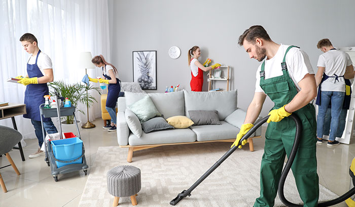 A diverse group of individuals tidying up a cozy living room together.