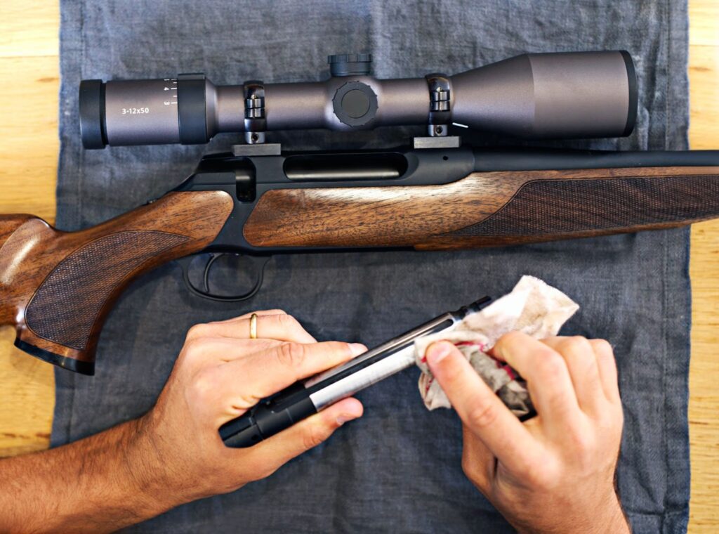 A man holds a gun in one hand and a pen in the other, symbolizing the balance between hunting and documentation.