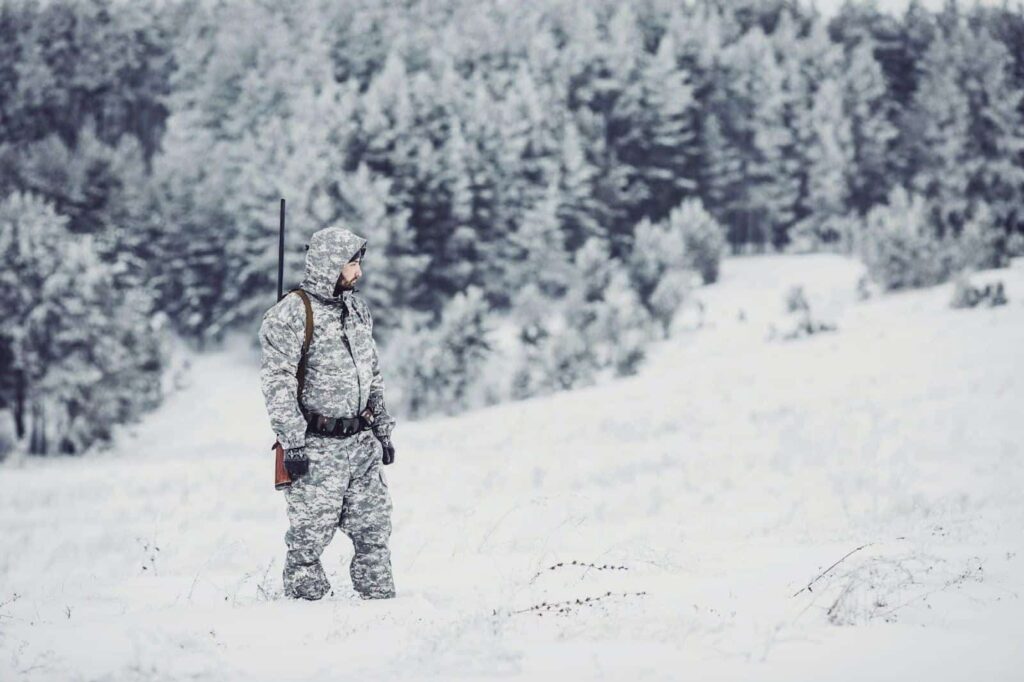 A man in camouflage blends into a snowy landscape