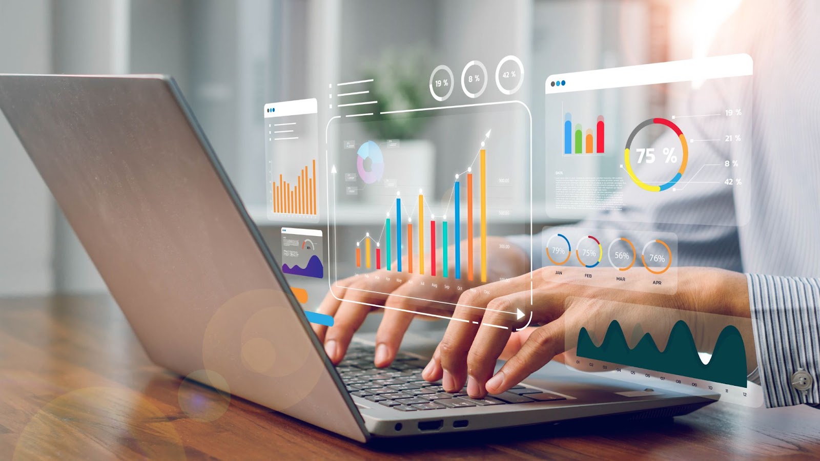 A person typing on a laptop with holographic charts and graphs displayed above the keyboard.
